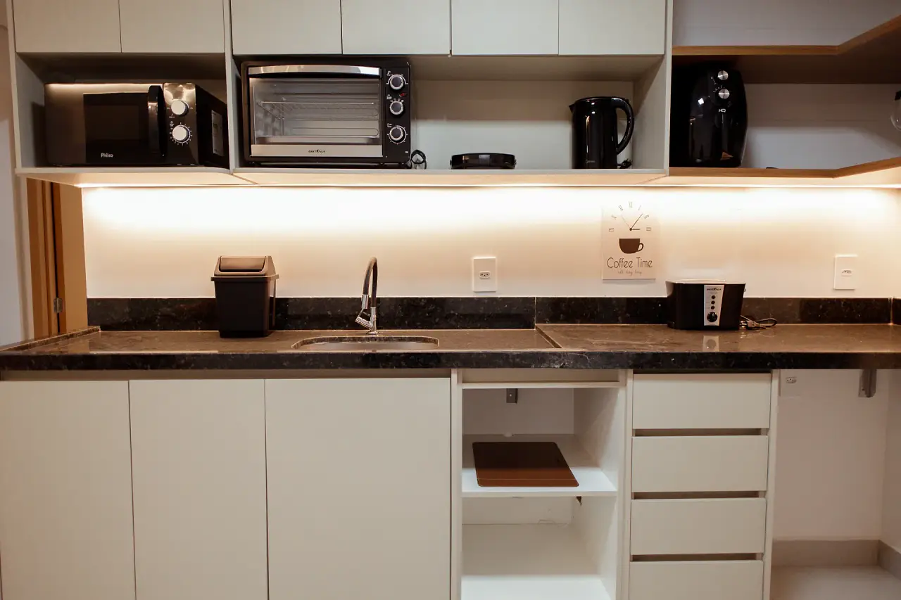 Cozinha equipada com micro-ondas, forno elétrico, cafeteira e armários