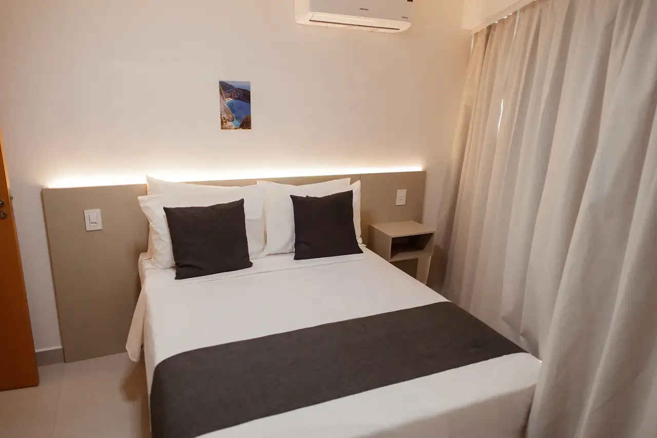Quarto de casal com cortinas e luz indireta na cabeceira