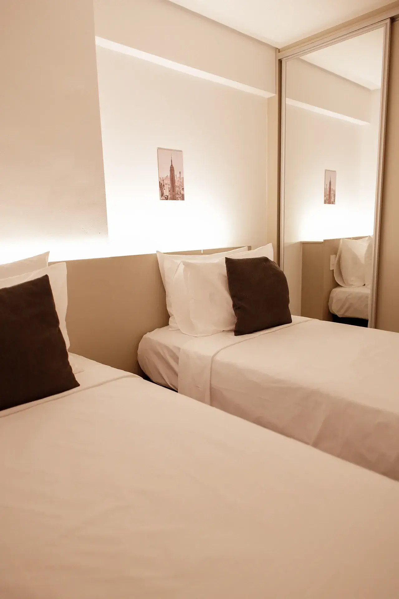 Quarto com duas camas de solteiro lado a lado e cabeceira iluminada