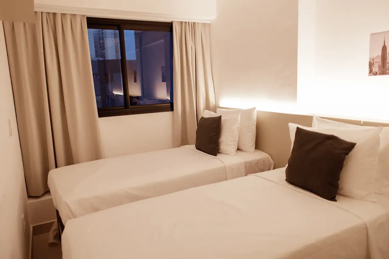 Quarto com duas camas de solteiro e janela