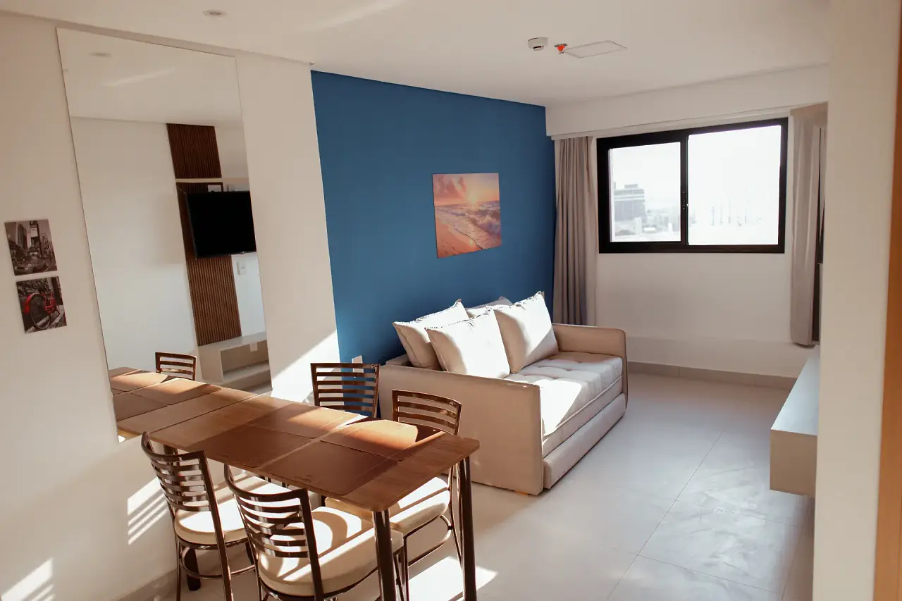 Sala com parede azul, sofá e mesa de jantar