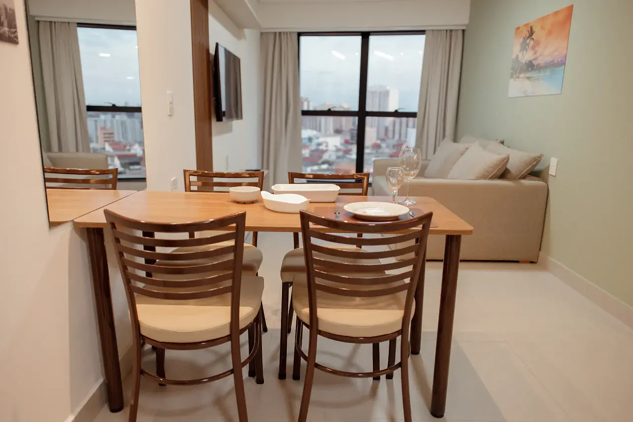 Sala do apartamento com mesa de jantar posta e vista da cidade