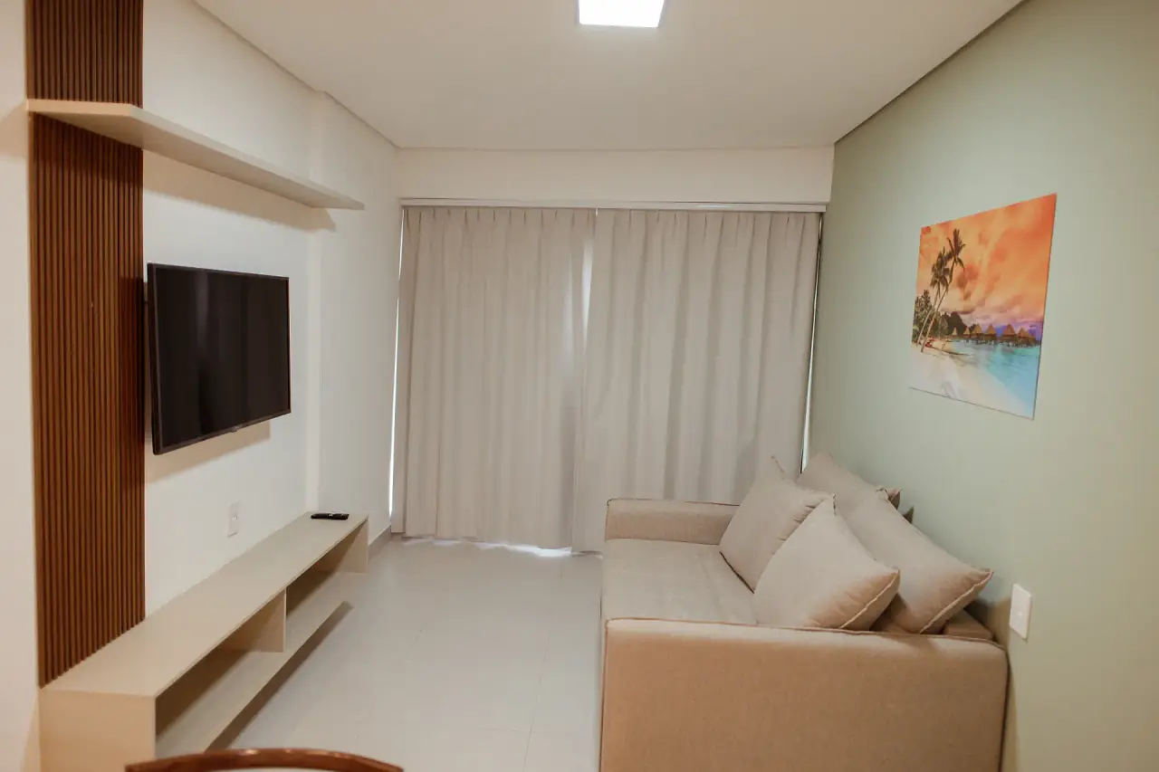 Sala com parede verde, sofá e TV